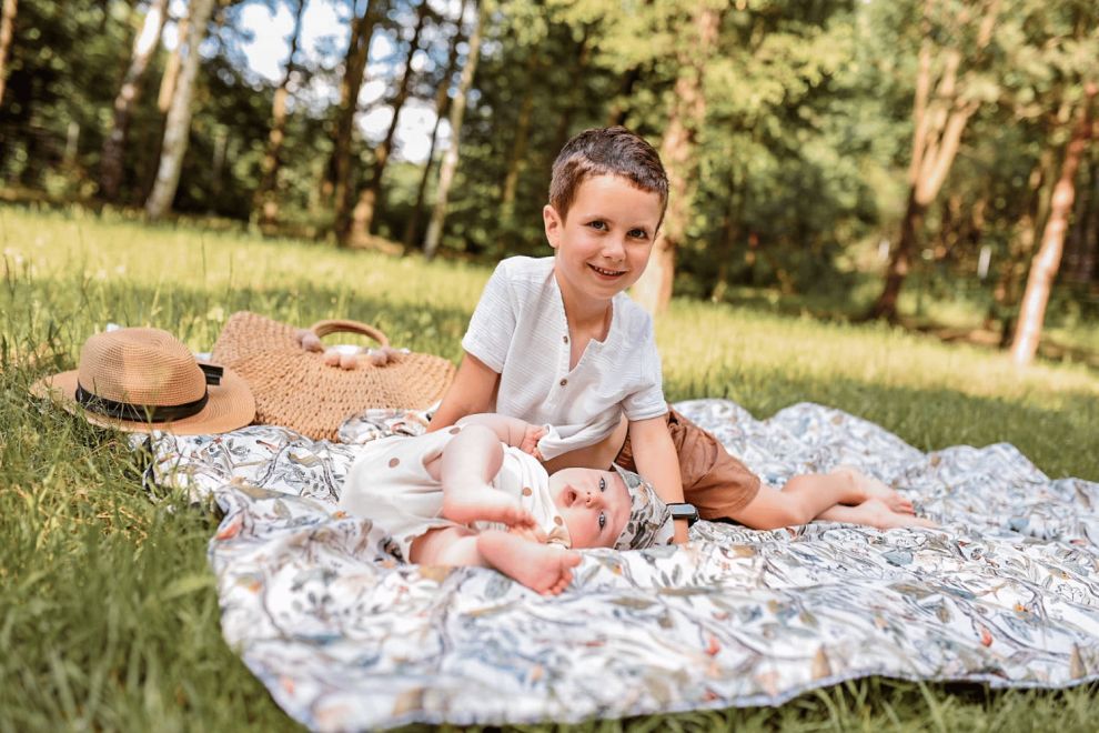 Bébé fille (6 mois) sur le tapis de pique-nique sur l'herbe en